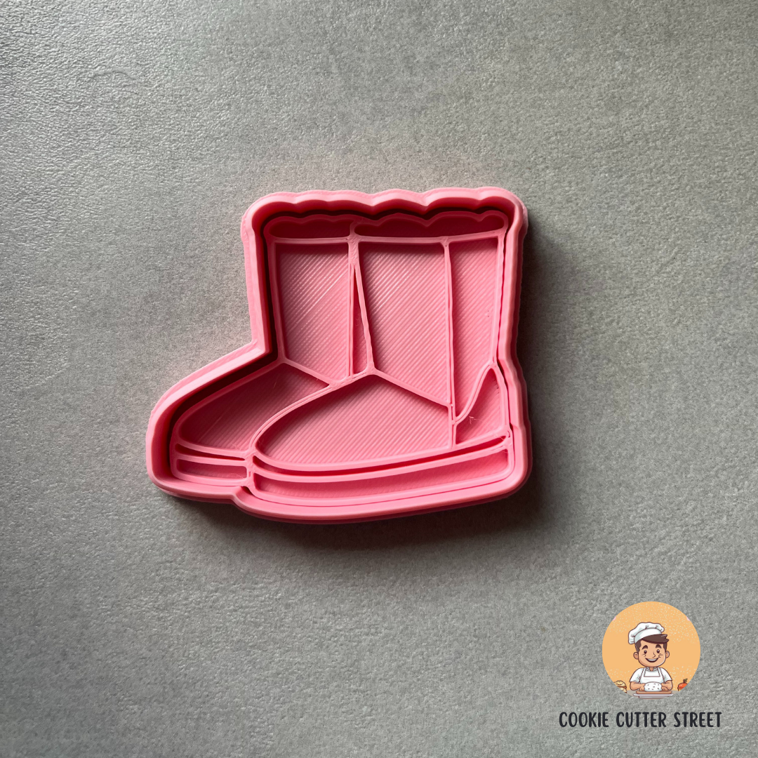 Pink boot-shaped cookie cutter on a gray background with 'Cookie Cutter Street' logo.