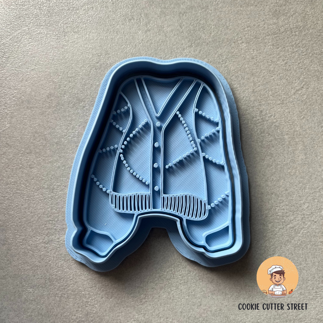 Blue cookie cutter shaped like a cardigan on a beige background