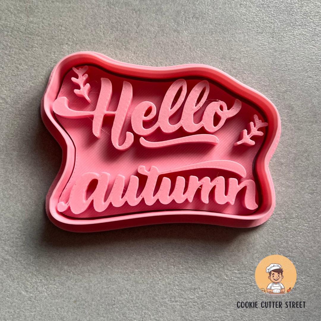 Pink cookie cutter with 'Hello autumn' text on a gray background