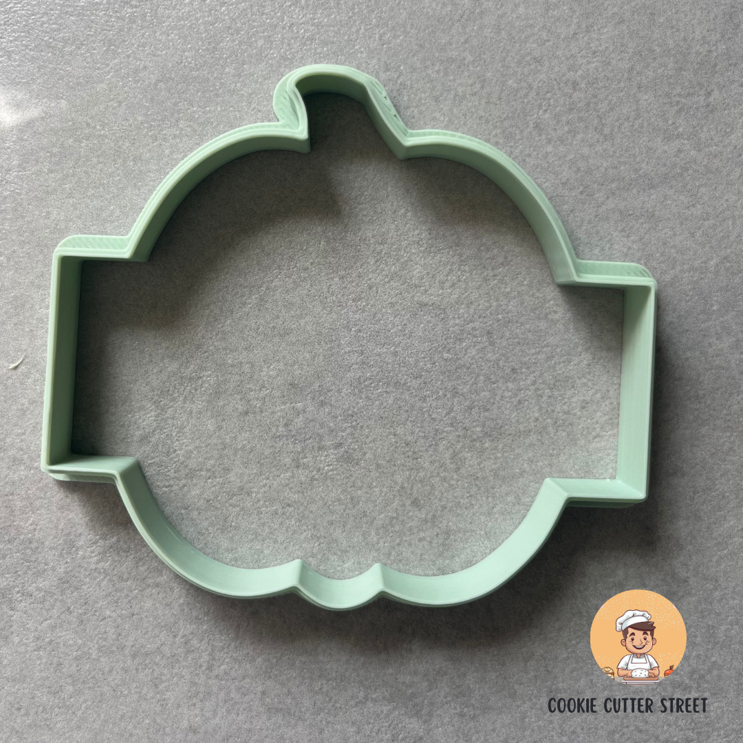 Green cookie cutter shaped like a pumpkin on a grey background