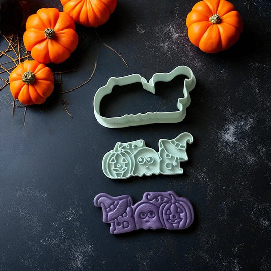 Set of Halloween-themed cookie cutters on a dark surface with pumpkins.